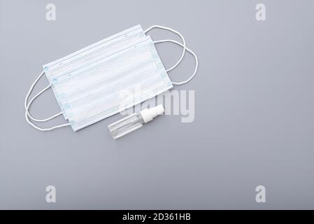 Masque chirurgical, masque médical et alcool antiseptique antibactérien gel pour les mains sur fond gris, image conceptuelle Banque D'Images