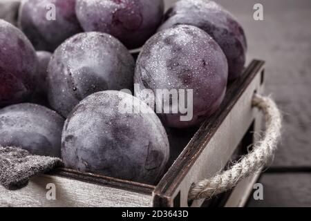 Grands prunes mûres dans un récipient sur la table Banque D'Images