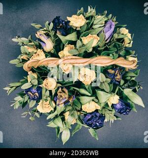 Bouquet de fleurs décolorées sur fond noir. Vue de dessus des roses bleues et jaunes séchées. Sécher les fleurs d'automne dans un panier en osier. Banque D'Images