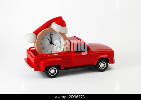 Concept de l'heure des fêtes de Noël et du nouvel an. Jouet de ramassage tendance rouge avec horloge et chapeau de Noël dans le coffre. Partie de l'ensemble. Banque D'Images