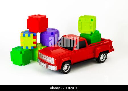 Cubes colorés dans un coffre rouge tendance. Jouet camion et puzzles. Concept contemporain de construction et de développement. Partie de l'ensemble. Banque D'Images