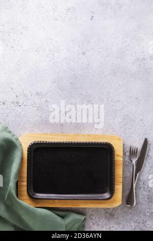 Plateau en fonte avec support, serviette et couverts sur la table avec espace de copie. La nourriture Banque D'Images
