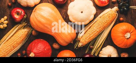 Fond de Thanksgiving, concept de récolte d'automne alimentaire. Table rustique avec pommes, citrouilles, noix, raisins et maïs sur table sombre avec espace de copie, top vie Banque D'Images