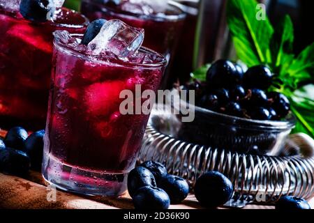 Cocktail alcoolique Darkside, avec liqueur, bleuet, jus de lime, glace pilée, outils de bar sur fond de bois vintage, concentration sélective Banque D'Images
