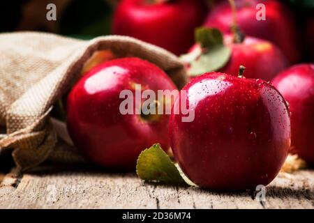 Pommes d'automne rouges avec gouttes sur fond rustique en bois, concentration sélective Banque D'Images