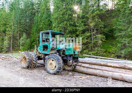 Récolteuse, véhicule forestier lourd (tracteur) avec chaînes sur roues, à côté des grumes de coupe dans les montagnes Tatra, en Pologne. Banque D'Images