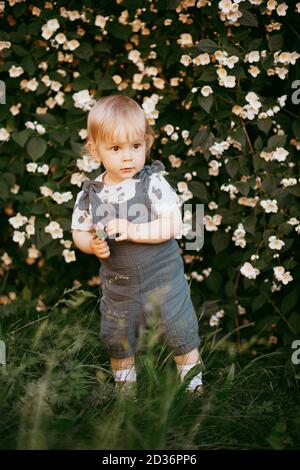 un enfant heureux vêtu d'une combinaison en mousseline repose sur l'herbe verte. Banque D'Images