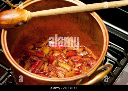 Le rhubarbe couve dans un pot de cuivre sur le poêle. Banque D'Images
