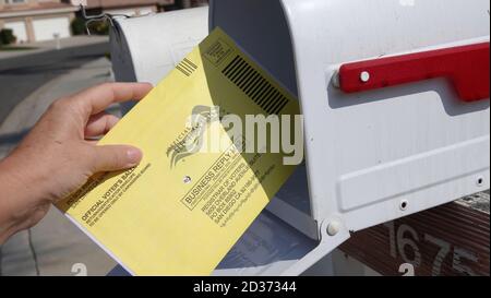 Gros plan de la main d'une femme retournant son bulletin de vote par courrier, le mettant dans la boîte postale. Éditorial illustré pris dans Vista, CA / USA le 7 octobre 2020. Banque D'Images