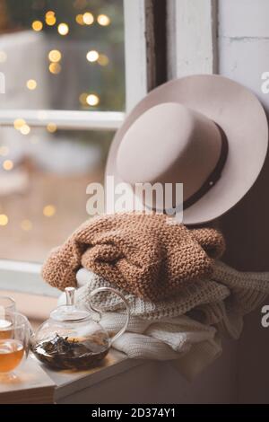 Concept d'algue chaud et confortable avec des chandails blancs et beiges et un chapeau au seuil de la fenêtre, tonicité Banque D'Images