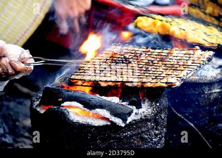 Brochettes de poulet frais grillées sur des flammes sur le simple poêle et feu à un vendeur de nourriture de rue dans les rues dans les vieux quartiers de Hanoi, Vietnam Banque D'Images