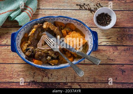 Ossobuco en sauce de cuisson avec carotte, oignon, poivron et champignons accompagnés de purée de patates douces dans une assiette vintage, en vue de dessus sur un Banque D'Images