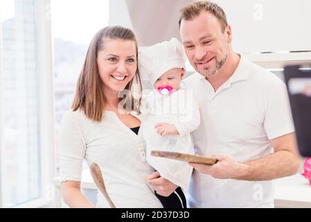 Des parents heureux debout dans la cuisine avec leur petite fille chef Banque D'Images