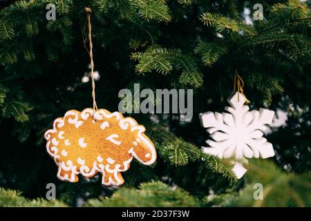 Jouet en bois d'arbre de Noël en forme d'agneau et un flocon de neige blanc sur des branches de sapin. Banque D'Images