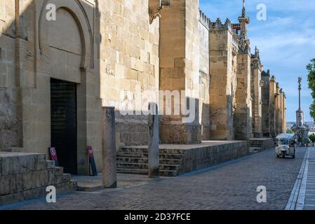 Rue de Cordoue pavée d'une statue à la fin et un très vieux mur en pierre Banque D'Images