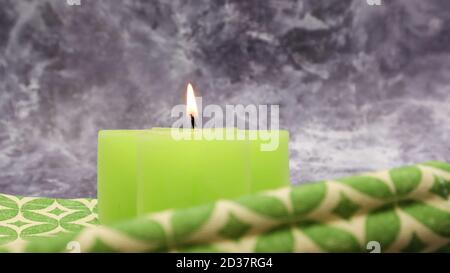 Composition avec une bougie allumée en vert sur une table avec une serviette en lin vert sur un magnifique fond de marbre gris. Place pour votre texte. Noël Banque D'Images