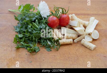 Racines de persil sur fond de bois, et quelques tomates Banque D'Images