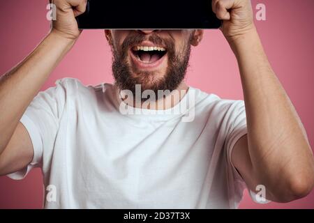L'homme annonce une tablette sur fond rose codes espace vue rognée des émotions t-shirt blanc modèle nouvelles technologies Banque D'Images