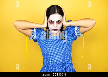 femme portant une poupée effrayante costume d'halloween sur fond jaune penser en train de regarder fatigué et s'ennuyer avec les mains sur la tête Banque D'Images