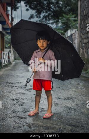 Kit Dalit jouant avec leur parapluie à Pokhara. Banque D'Images