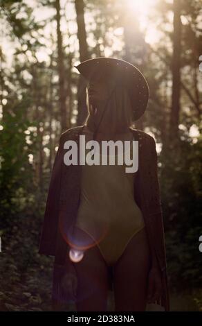 Hippie femme en maillot de bain et chapeau de cow-boy dans la forêt au coucher du soleil. Banque D'Images