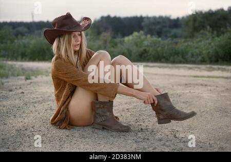 Hippie femme en maillot de bain et chapeau de cow-boy dans la prairie au coucher du soleil. Banque D'Images