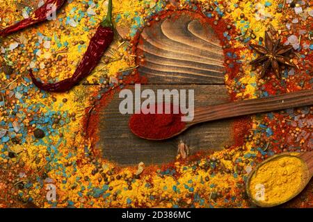 Composition du condiment en forme de coeur. Cuillères à bois avec curcuma, paprika, étoiles anis, piment et assaisonnements épars. Ensemble d'épices sur fond de bois. Cuisine et saveurs Banque D'Images