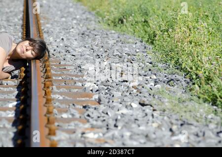 Femme à l'écoute d'un train entrant sur la voie ferrée. Banque D'Images