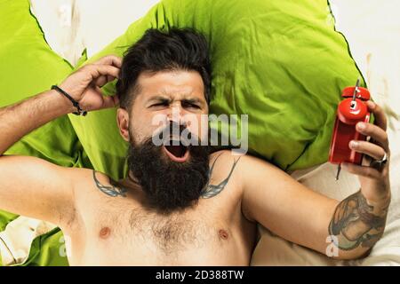 Concept d'alarme. Un bel homme dort dans la chambre - allongé sur le lit. Homme de sommeil. Homme barbu dormant sur le lit dans la chambre. Banque D'Images