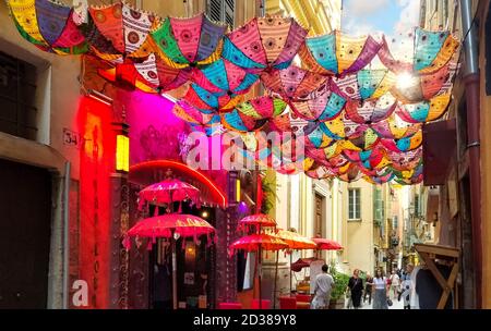 Les touristes passent sous une verrière colorée de parasols devant un magasin dans la vieille ville historique de Nice France, sur la Côte d'Azur. Banque D'Images