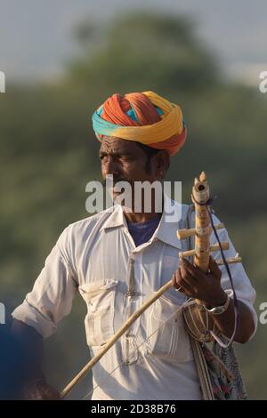 Un homme habillé de vêtements traditionnels du rajasthani jouant du violon d'instrument de musique au festival Pushkar à Pushkar, Rajasthan, Inde, le 19 novembre 2018 Banque D'Images