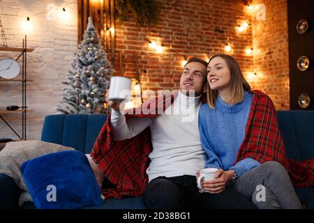 Beau jeune couple à la maison buvant du café le matin de Noël. Passer du temps ensemble, les relations et les personnes concept. Vacances d'hiver Banque D'Images
