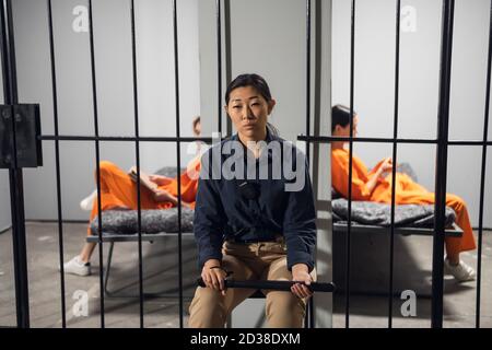 Une heure tranquille dans une prison pour femmes, les prisonniers se reposant sur leur lit, un garde sur une chaise dans le couloir. Banque D'Images