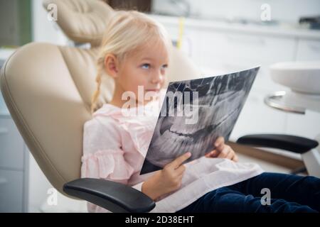 Une petite fille à l'écoute d'un médecin, qui lui explique ce qu'elle voit sur la radiographie. Banque D'Images