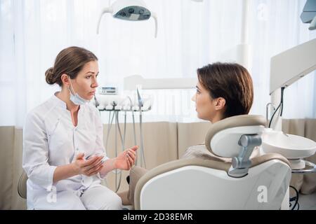 Une femme dentiste consultant sa patiente à la clinique. Banque D'Images