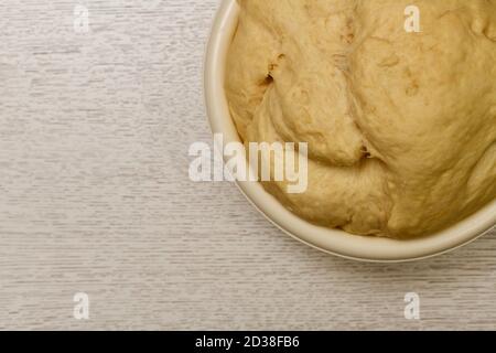 La pâte à levure soufflée s'est levée dans un grand bol rond et léger. Fragmenter en haut à droite, sur le dessus de la table. Banque D'Images