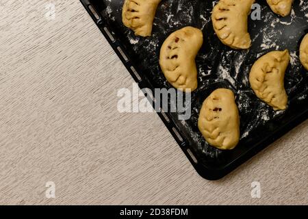 Tartes sucrées à base de pâte à levure, produits semi-finis crus. Fragment d'un coin sur un plan de travail de couleur claire. Banque D'Images