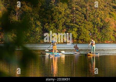 Paddleboarders et un kayakiste appréciant une soirée sur l'eau au coucher du soleil sur le lac de Stone Mountain au parc de Stone Mountain près d'Atlanta, Géorgie. (ÉTATS-UNIS) Banque D'Images