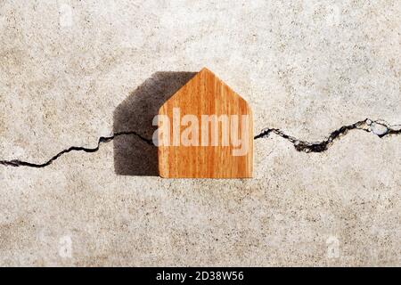 Maison miniature sur fond de texture de mur de ciment fissuré. Vue de dessus Banque D'Images