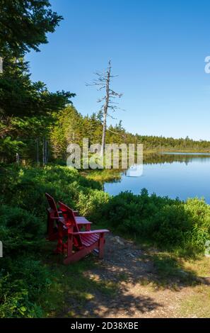 Chaises rouges dans un point de vue panoramique surplombant le lac Laverty. Forêt d'épinettes et de nains sur la rive du lac. Parc national Fundy, Nouveau-Brunswick, Canada. Banque D'Images