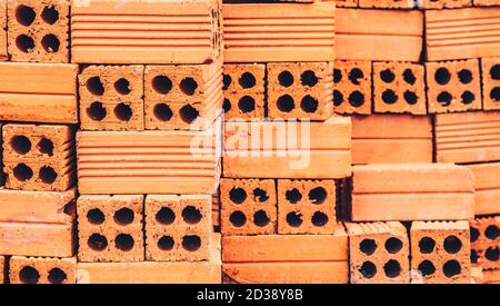 Gros plan de la pile de briques rouges neuves avec des trous empilés dans le mur des rangées. Magasin de briques prêt pour la construction ou la vente. Contexte matériaux de construction de bâtiment Banque D'Images