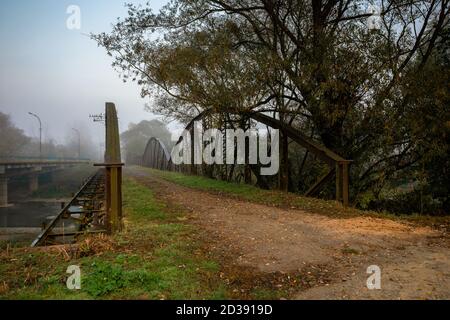 pont de métal abandonné dans le brouillard du matin. construction dangereuse dans les paysages de campagne automnale au lever du soleil Banque D'Images