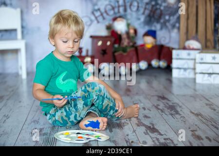 Adorable enfant blond, garçon, peint ses pieds avec des peintures colorées à la maison Banque D'Images