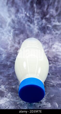 Une bouteille en plastique de lait ordinaire frais sur fond en marbre gris foncé ou en béton. Vue de face rapprochée. Concept de la Journée mondiale du lait. Liquide nutritif. Ver Banque D'Images