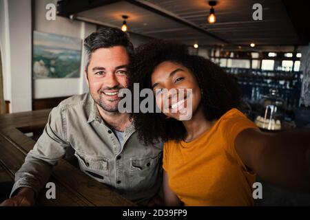 couple multi-course souriant dans l'appareil photo dans un café brillant boutique Banque D'Images