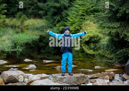 Des gens heureux dans la forêt sur les rochers près de l'étang, jouant dans la pluie, jour d'automne Banque D'Images