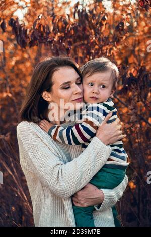 Petit garçon mignon dans les bras de sa mère. Femme à la maison portant son fils nouveau-né. Banque D'Images