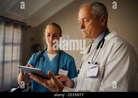 Un médecin et une infirmière de sexe masculin discutent ensemble des résultats sur un tablette numérique Banque D'Images