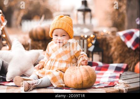 Bébé fille souriante 1-2 ans vêtu d'une robe jaune élégante et d'un chapeau tricoté posant sur la saison d'automne décor extérieur gros plan. Regarder l'appareil photo. CHIL Banque D'Images