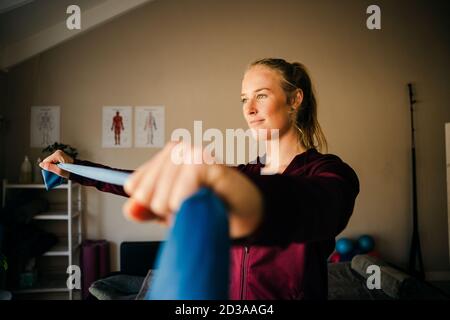 Magnifique blanc femme physio étirant bleu de la contrebande en se tenant en studio. Banque D'Images